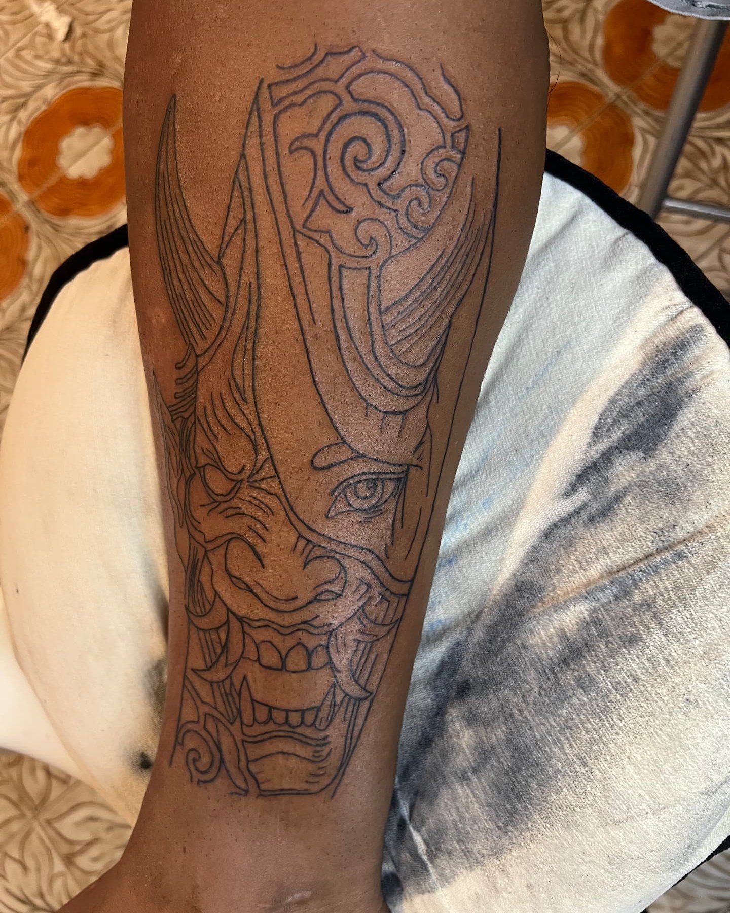 Lineado de la máscara hannya durante el proceso del tatuaje en una pierna