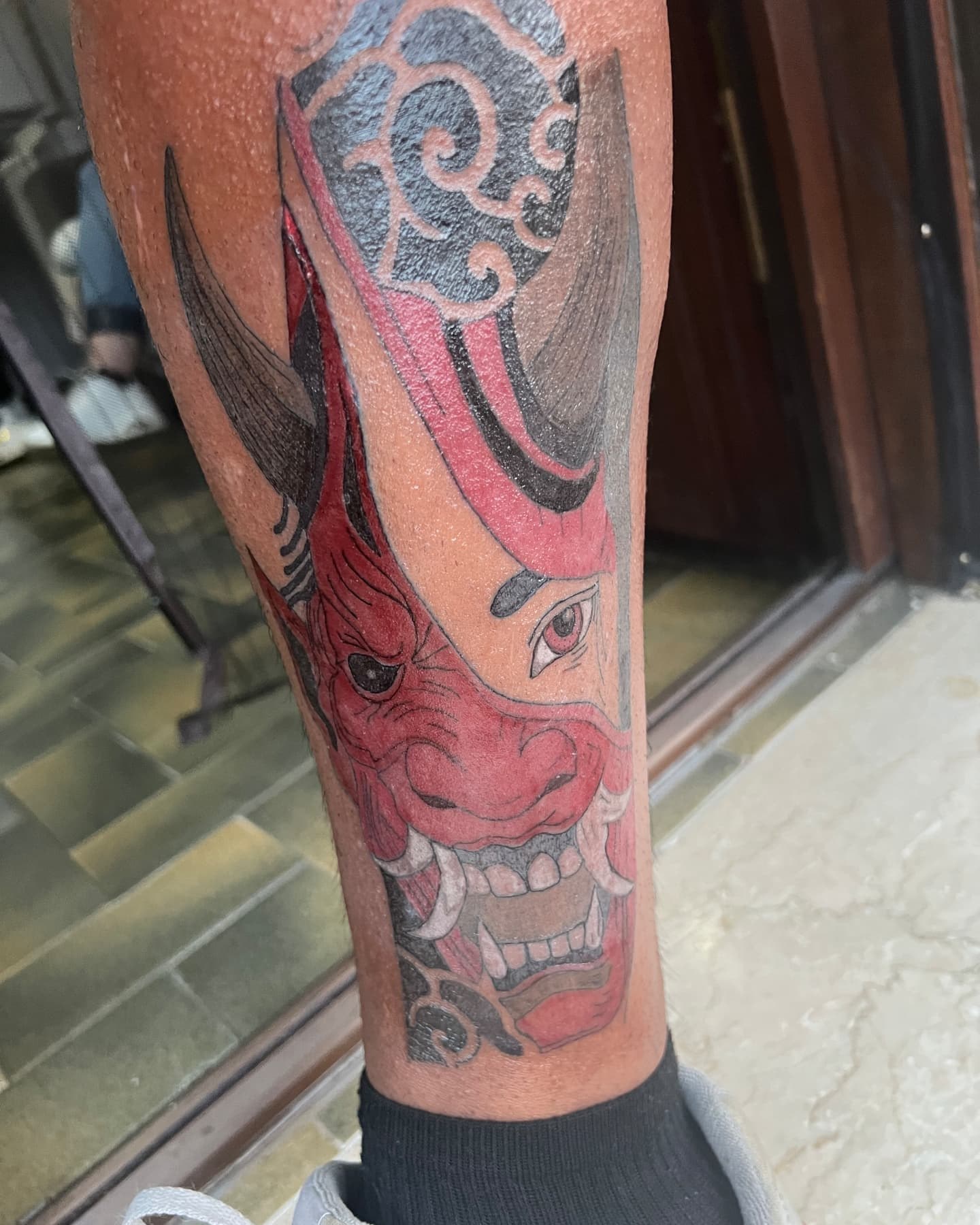 Tatuaje terminado de máscara hannya japonesa en rojo y negro sobre una pierna